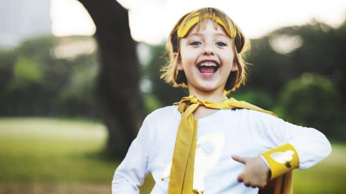 Young caucasian girl smiling wearing superhero costume in the park
